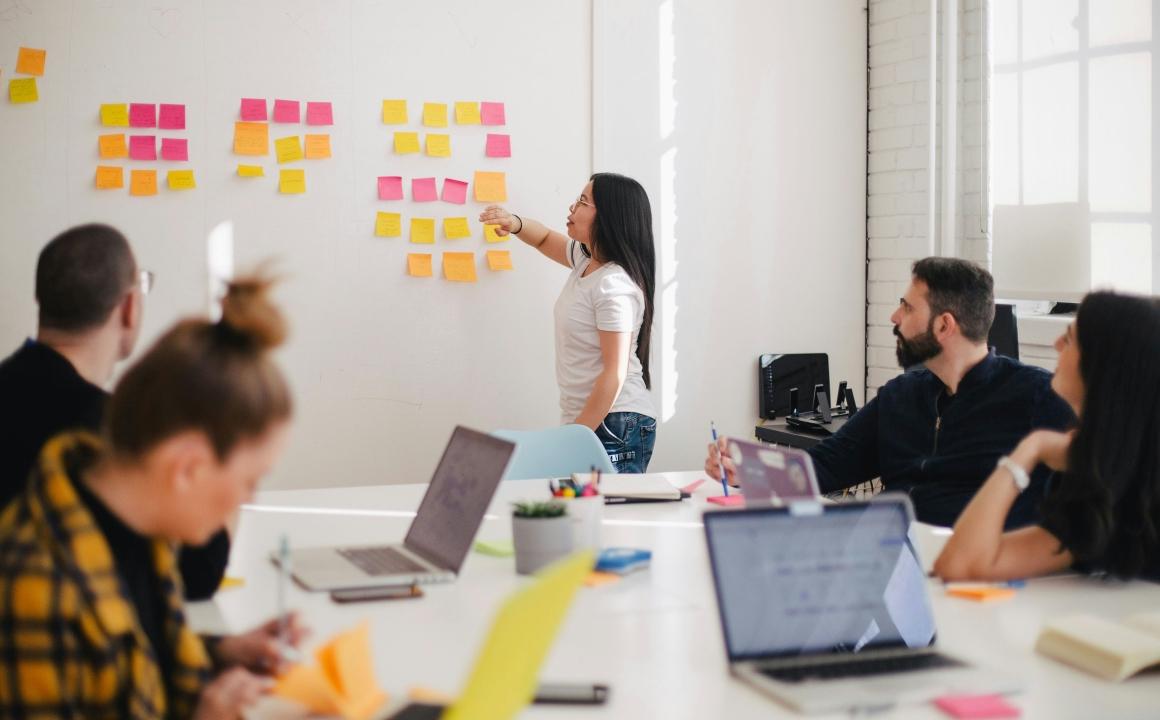 Woman leading meeting in conference room with post-it notes on a whiteboard